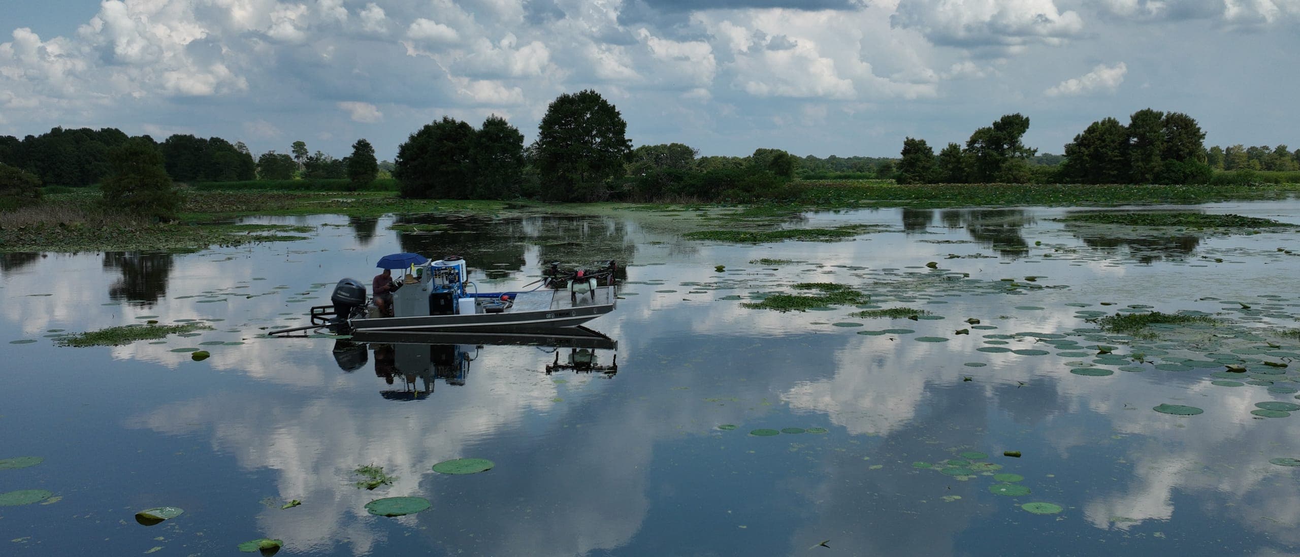 An application boat on a mirror-calm Texas lake reflecting the far shoreline
