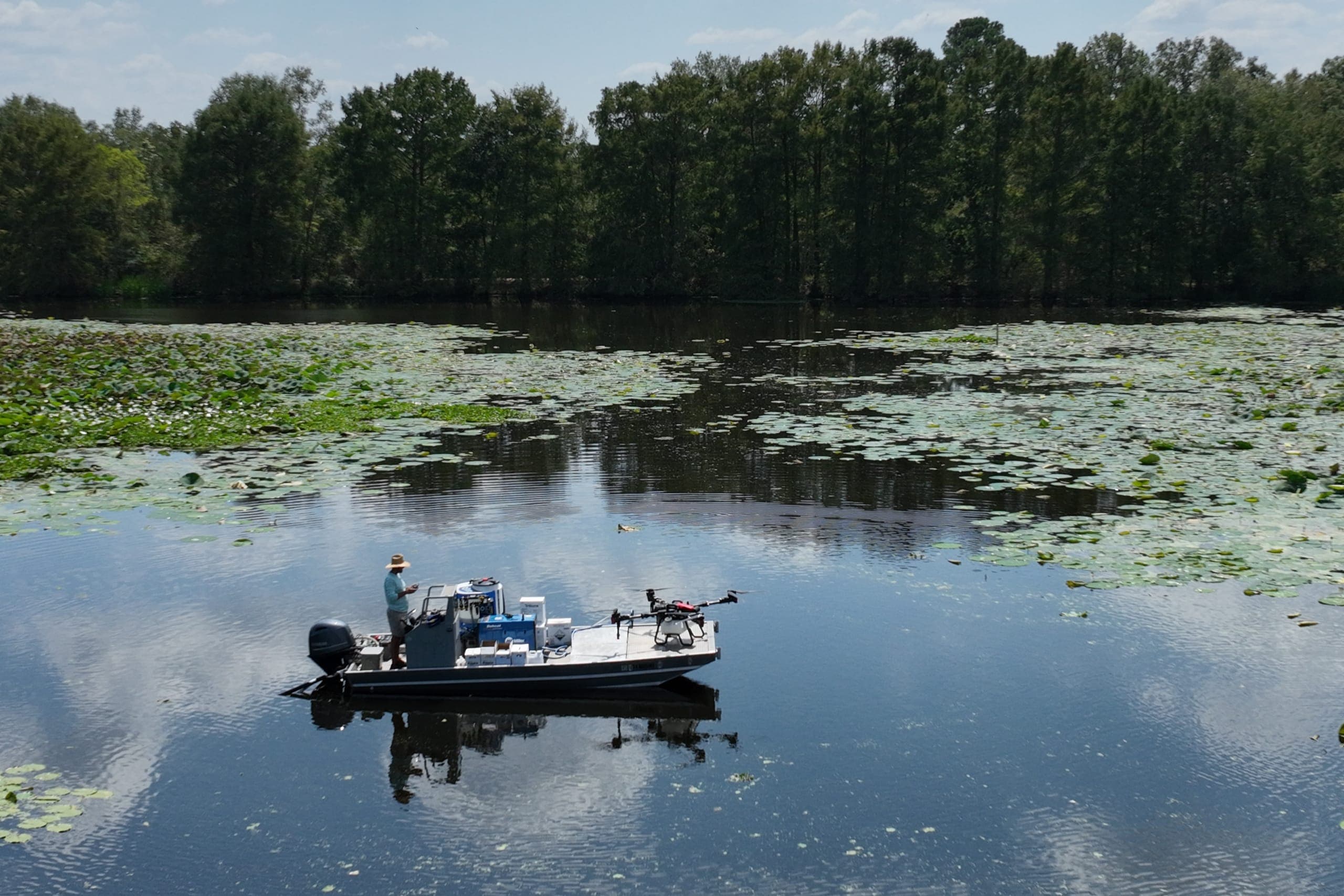 A Shoreline operator on a boat readying a spray drone over the water
