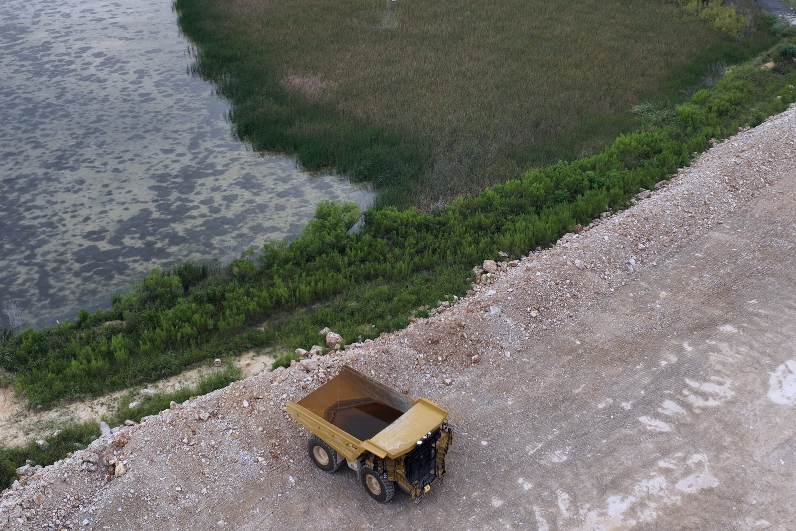 Aerial view of a work-site haul road and truck beside a treated shoreline